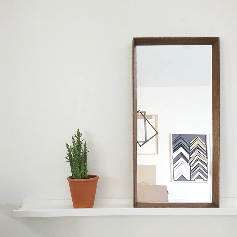 framed mirror in which the reflection of several frame corners can be seen