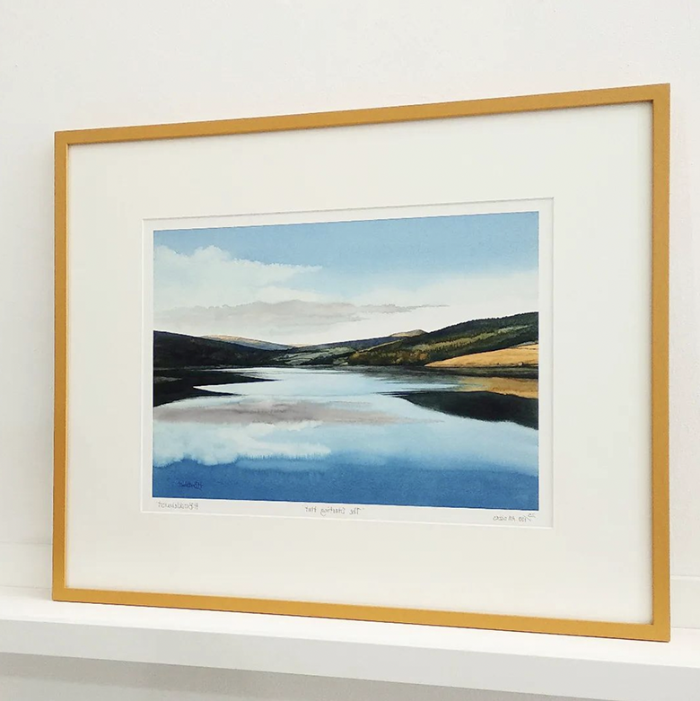 print of mountains around a body of water mounted and framed in yellow frame