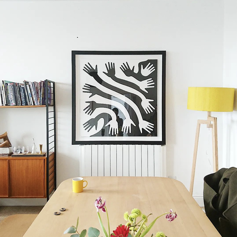 monochrome print of tessellating hands and forearms framed in chunky black frame